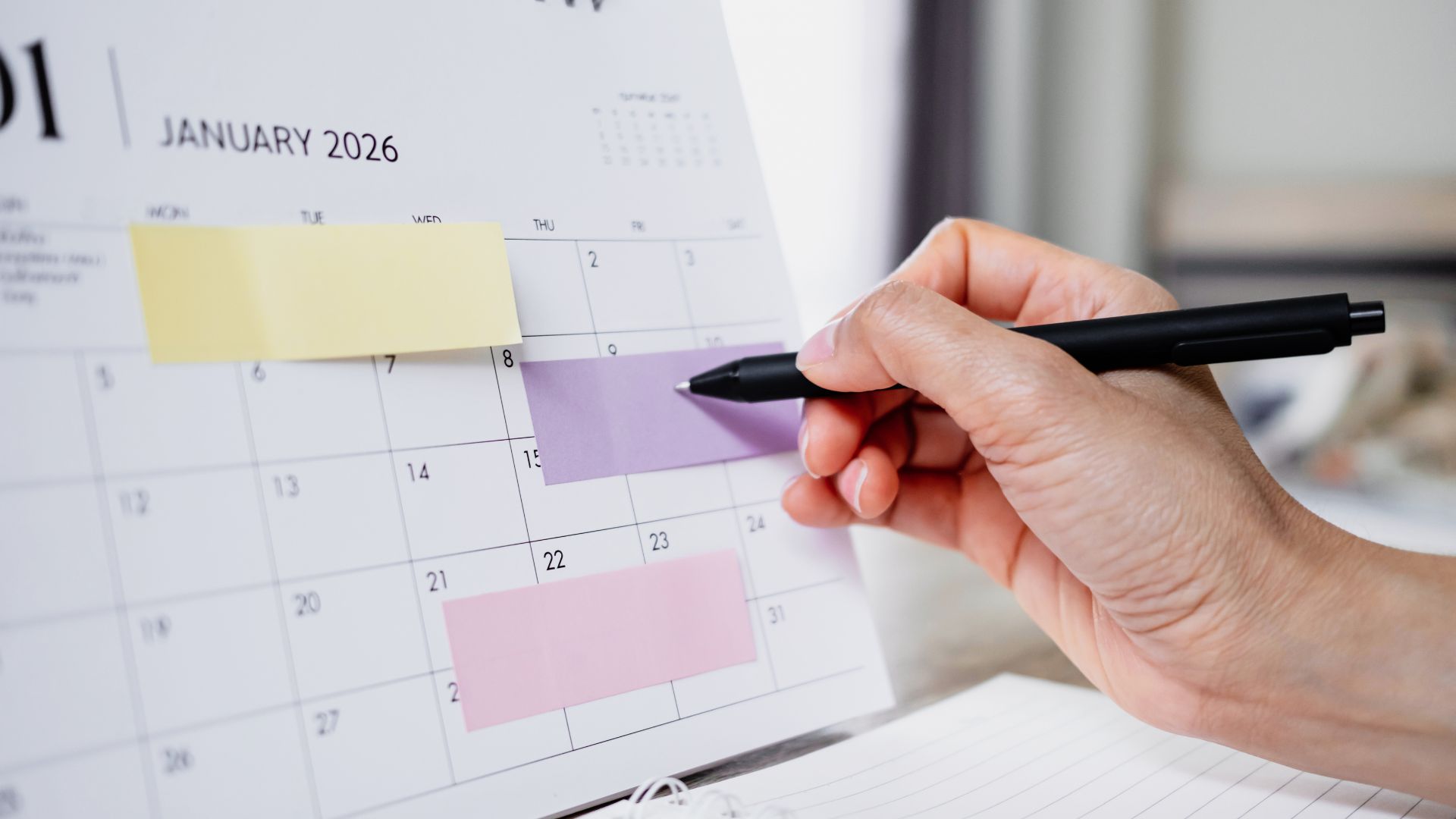 Hand marking dates on a calendar with sticky note reminders, representing a 30-day business credit building plan